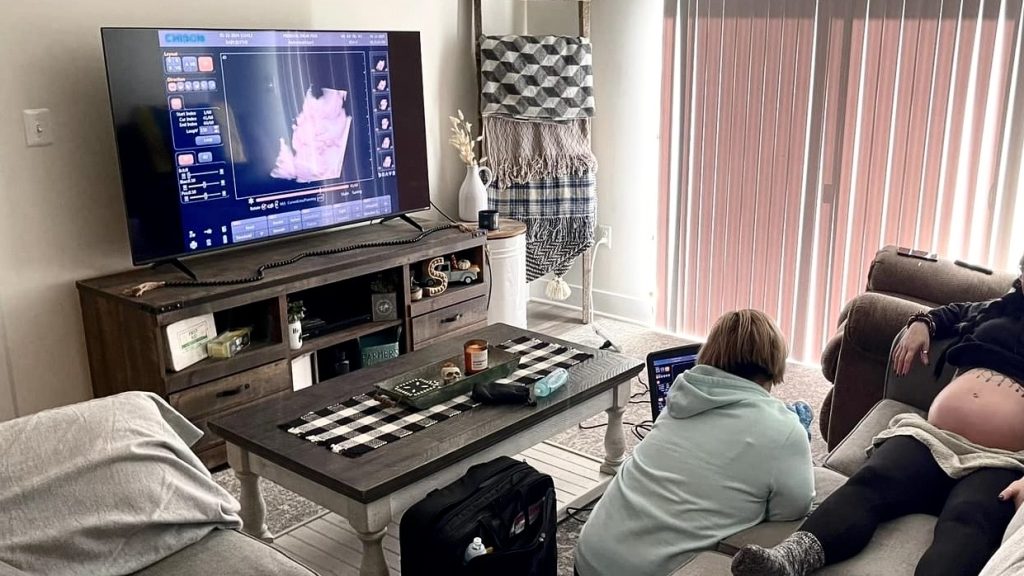 Family watching mobile 3D ultrasound session on TV in living room in Bel Air, Maryland
